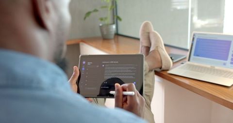 Man Relaxing with Tablet and Laptop in Home Office Environment
