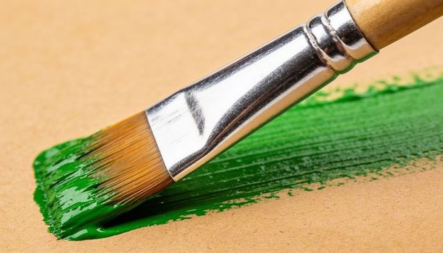 Painting bright green brush stroke on kraft paper with flat brush closeup, glossy texture