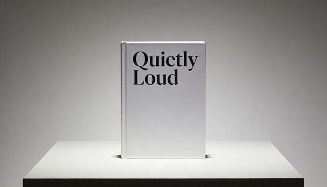 Minimal white hardcover book quietly loud on pedestal with bold serif typography