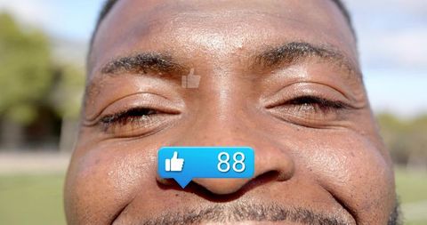 Smiling African American man squinting in sun showing thumbs-up notification 88