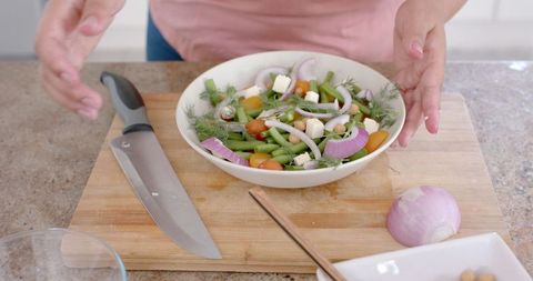 Woman Preparing Fresh Vegetable and Feta Cheese Salad in Kitchen