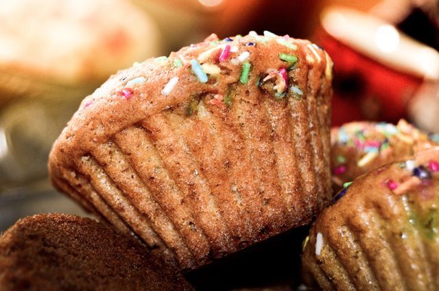 Close-up view of a freshly baked muffin adorned with colorful sprinkles. Perfect for use in bakery advertisements, food blogs, recipe websites, or culinary magazines to highlight homemade baked goods.