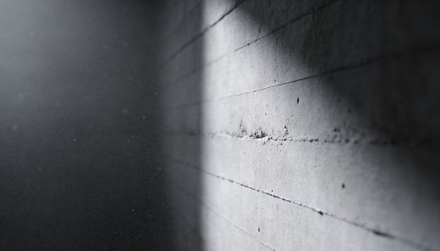 Rough cast concrete wall catching moody light and floating dust motes