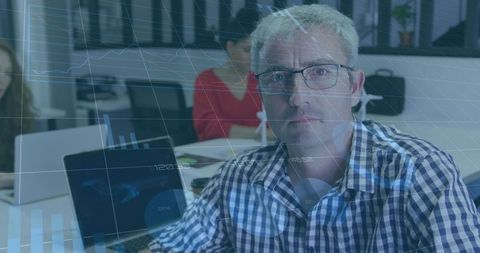 Senior professional analyzing data analytics on laptop during collaborative team meeting