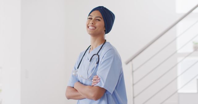 Image of happy biracial female doctor in hijab looking at camera. Health, medicine, prevention concept.