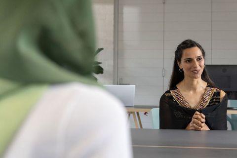 Indian businesswoman leading discussion with colleague in modern minimalist office