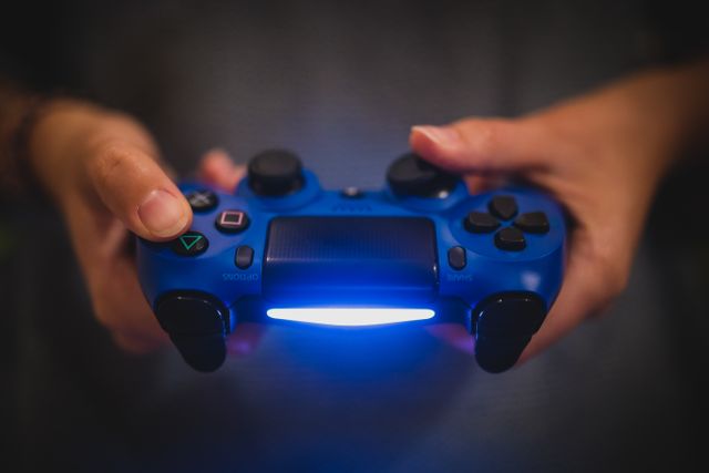 Photo showing hands holding blue game controller. Suitable for content involving gaming, technology, video games, entertainment, or console gaming. Can be used for articles, websites, advertising, or tutorials related to gaming and technology.