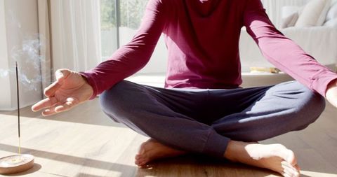 Man meditating indoors with incense creating tranquil atmosphere