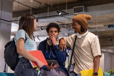 Multicultural students chatting and studying in modern industrial campus lounge