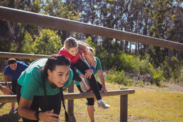 Group of women participating in a boot camp, navigating an outdoor obstacle course. Ideal for promoting fitness programs, outdoor activities, teamwork, and healthy lifestyles. Suitable for use in advertisements for fitness boot camps, sports events, and health-related campaigns.
