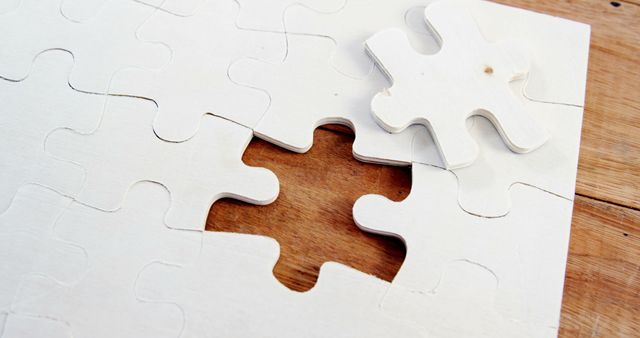 A nearly complete jigsaw puzzle on a wooden surface is missing one piece, with copy space. Its completion symbolizes problem-solving and the satisfaction of finding a missing element in a broader picture.