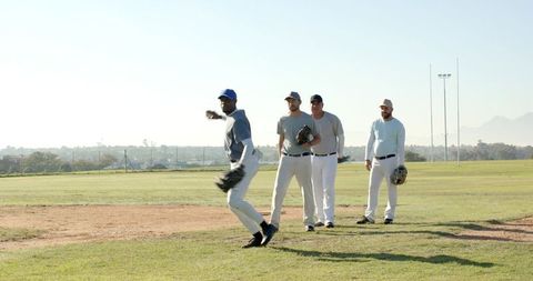 Multiracial Baseball Team Practicing Fielding Drill on Sunny Grass Diamond