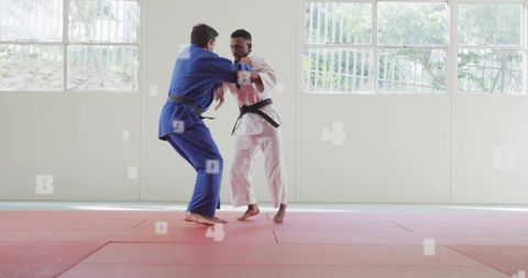 Judo sparring duo training with gis and black belts on red mats with numeric overlay