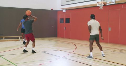 African american teammates practicing passing and shooting inside gym basketball court