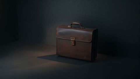 Resting vintage brown leather briefcase with distressed patina, top handle and metal lock