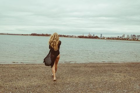 Woman with Long Hair Walking on Beach in City View