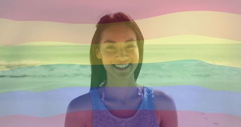 Smiling woman with rainbow overlay on sunny beach