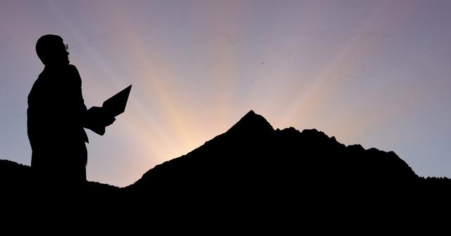 Digital composite of Silhouette businessman on mountain during sunset