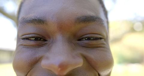 Close-up of person smiling outdoors in sunlight