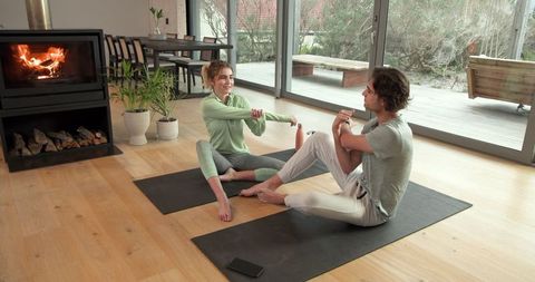 Couple practicing yoga in modern living room with fireplace