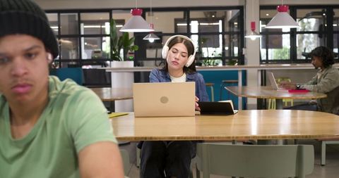 African american students studying in coworking space with laptops and white headphones