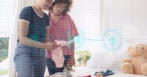 Two women organizing wardrobe in sunlit bedroom with digital data overlay