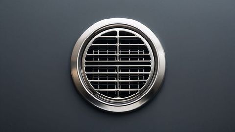Circular metal vent on gray background with silver frame
