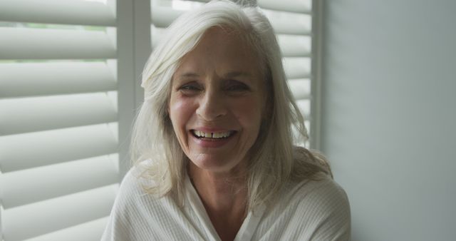 Smiling Senior Woman with Gray Hair Sitting by Window Blinds - Download Free Stock Images Pikwizard.com