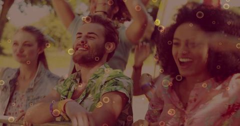 Smiling friends enjoying outdoor music festival while leaning on barrier with wristbands