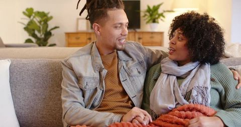Young couple sharing cozy conversation on living room sofa holding hands and smiling
