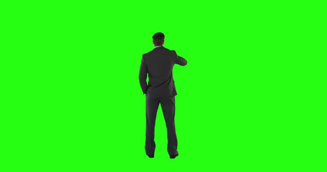 Businessman standing against a green screen background, wearing a suit, seen from back view. Ideal for use in corporate presentations, marketing materials, and business communications. The green screen allows for easy background replacement, making it versatile for digital content creation.
