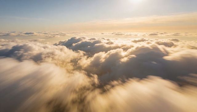 Golden Clouds Drifting Over Sunlit Horizon at Sunrise High Altitude Aerial View