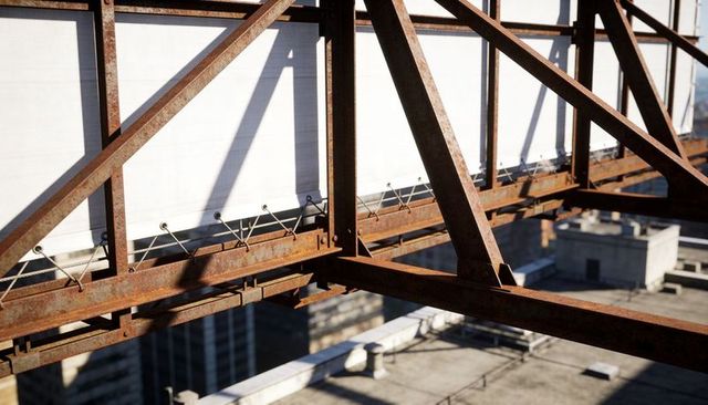 Rusted steel billboard truss casting sharp shadows over white rooftop panels in city