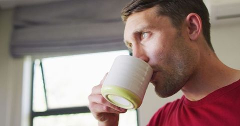 Thoughtful man drinking coffee by bright window
