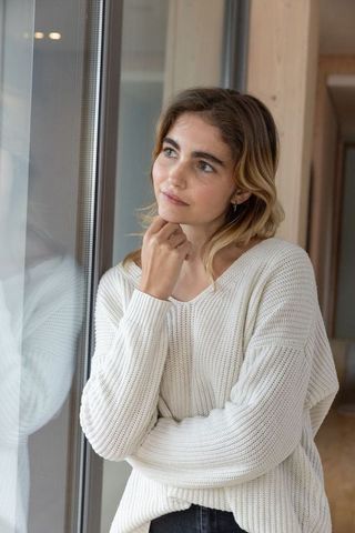 Thoughtful Woman in Modern Wood-Accent Interior Looking Out Glass Window