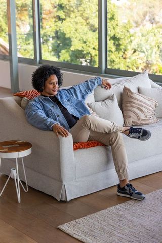 African american man reclining on light-gray sofa in sunlit modern living room lifestyle