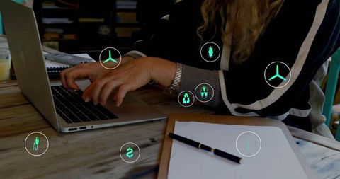 Mature woman typing on laptop surrounded by green renewable energy and finance icons