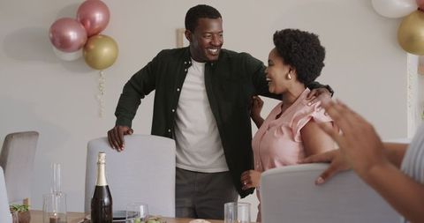 Friends celebrating around dining table with food and wine