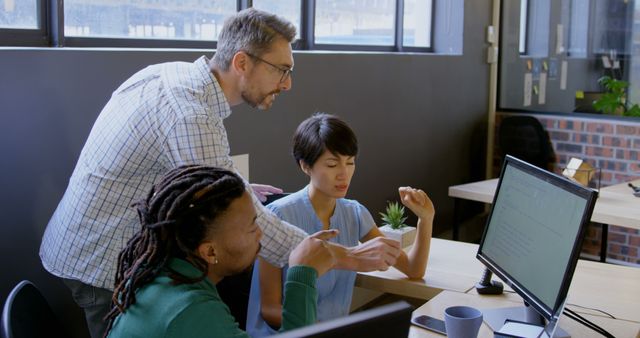 Three professionals collaborating and working on a project in a modern office, focused on computer screen. Perfect for depicting teamwork, project management, office environments, corporate training materials, and technology use in business settings.