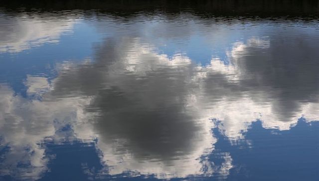 Rippling cloud reflections on lake water creating abstract gray and blue landscape