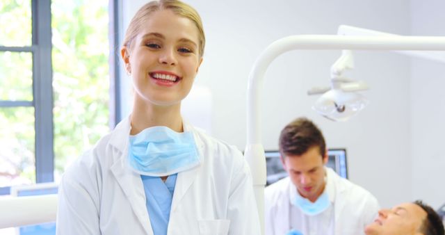 Smiling Female Dentist in Dental Clinic with Colleagues Treating Patient - Download Free Stock Images Pikwizard.com