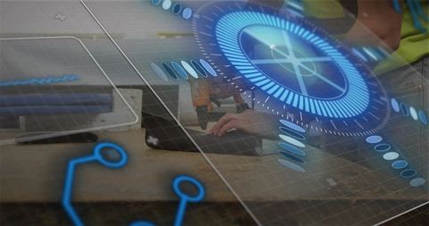 Engineers collaborating at workbench typing on laptop with AR interface overlay