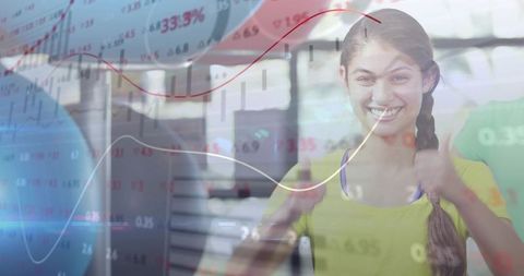 Smiling business woman giving two thumbs up with overlaid financial charts showing success