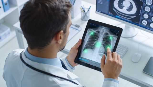 Doctor reviewing chest x-ray on tablet with ai markers annotating lungs for diagnosis