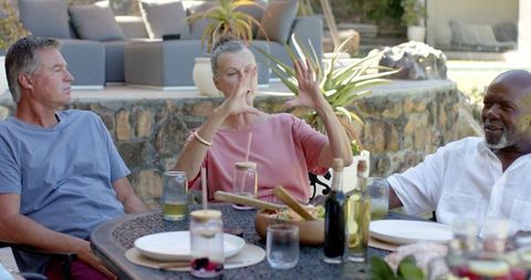 Diverse Friends Socializing on Patio with Salads and Drinks