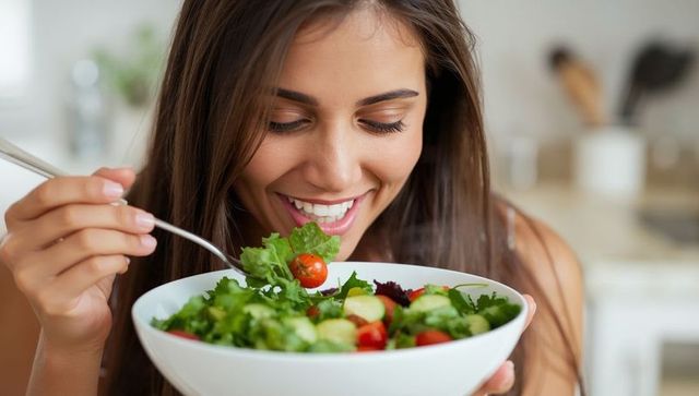 Woman enjoying fresh green salad at home kitchen