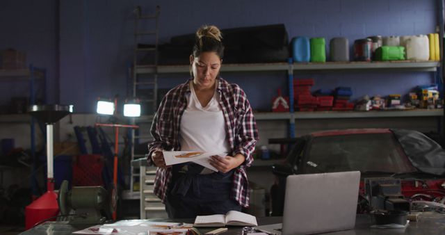 Female auto mechanic reviewing documents in industrial garage - Download Free Stock Images Pikwizard.com