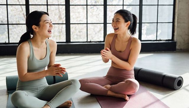 Laughing Asian Women Clapping on Yoga Mats in Bright Sunlit Studio