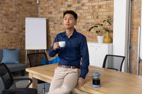 Professional Man Holding Coffee Cup in Modern Office