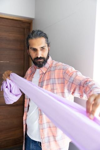 Man Holding Light Purple Fabric in Casual Home Setting
